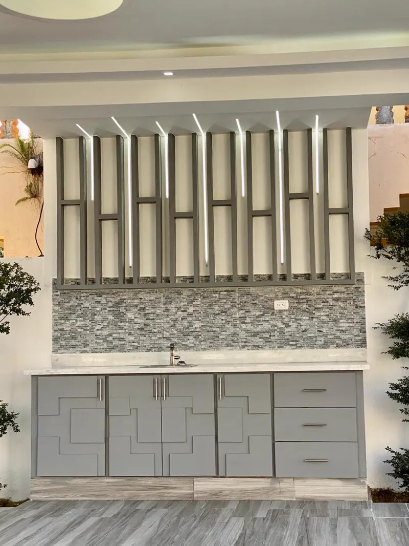 Bar exterior con pared de piedra y gabinetes grises